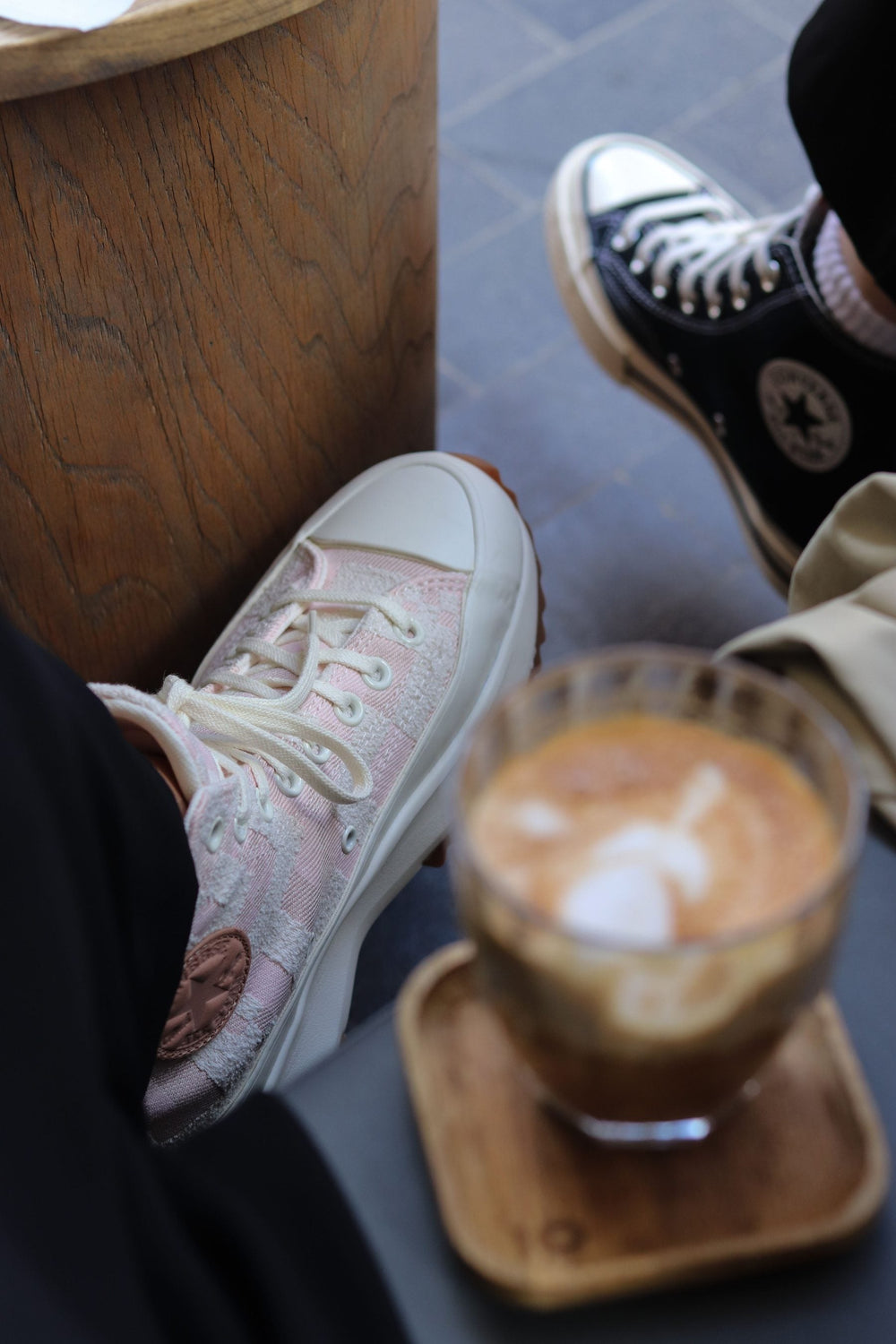 Cup of coffee beside casual athletic shoes at a cafe