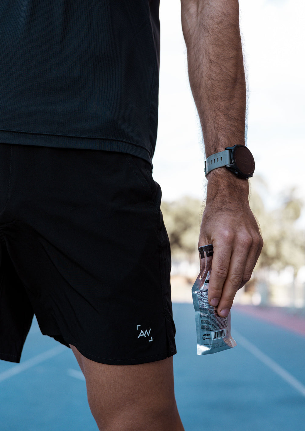 Endurance athlete holding an energy gel on a running track