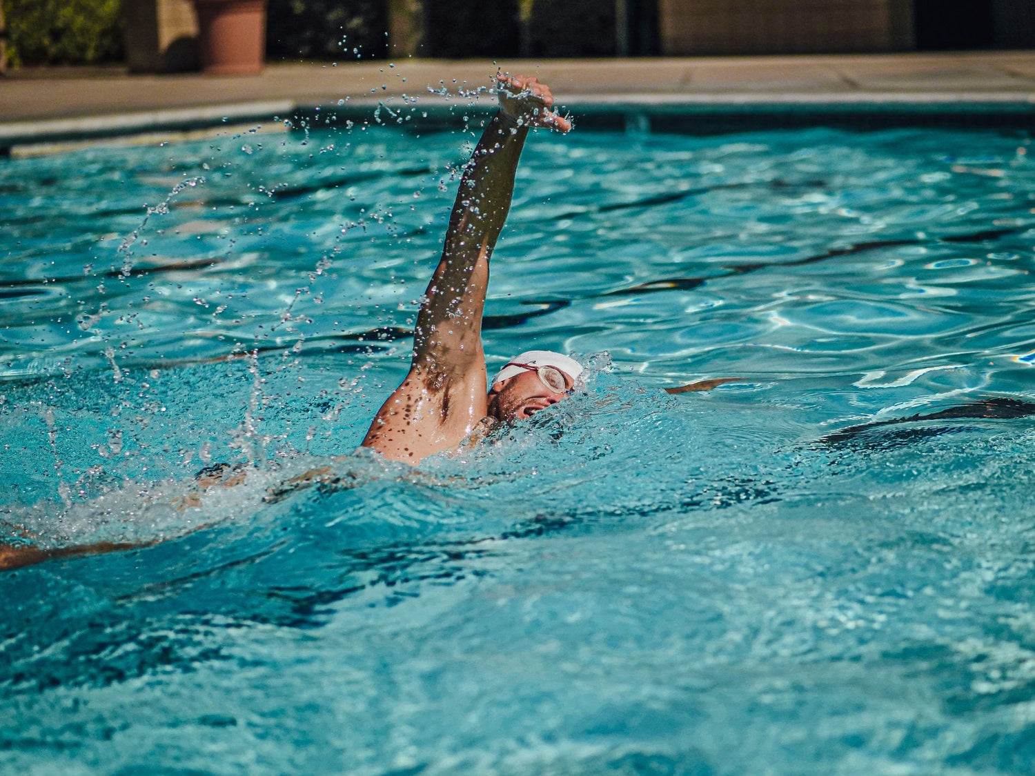 Adult swimmer learning freestyle in a bright outdoor pool