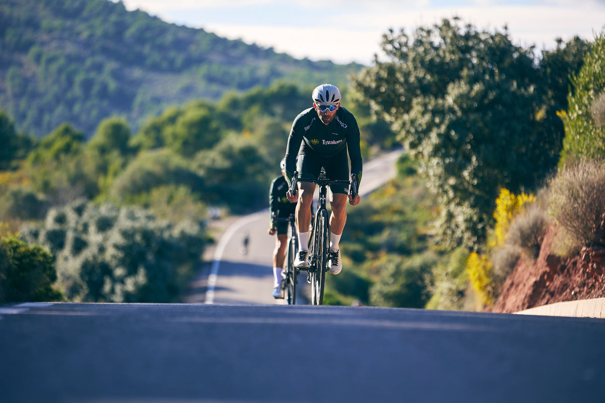 Road cyclist training uphill on a rural road for an average cycling speed guide