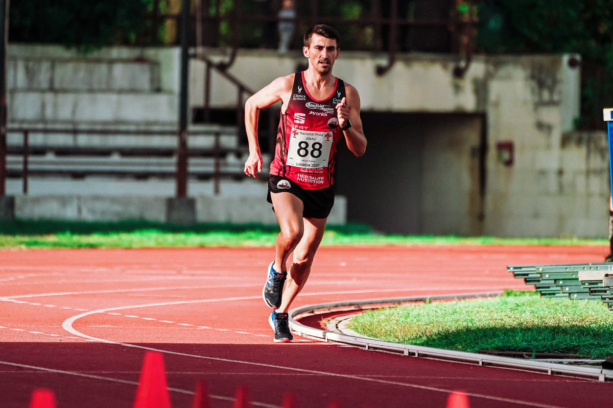 Runner holding a hard controlled pace on an athletics track during threshold training