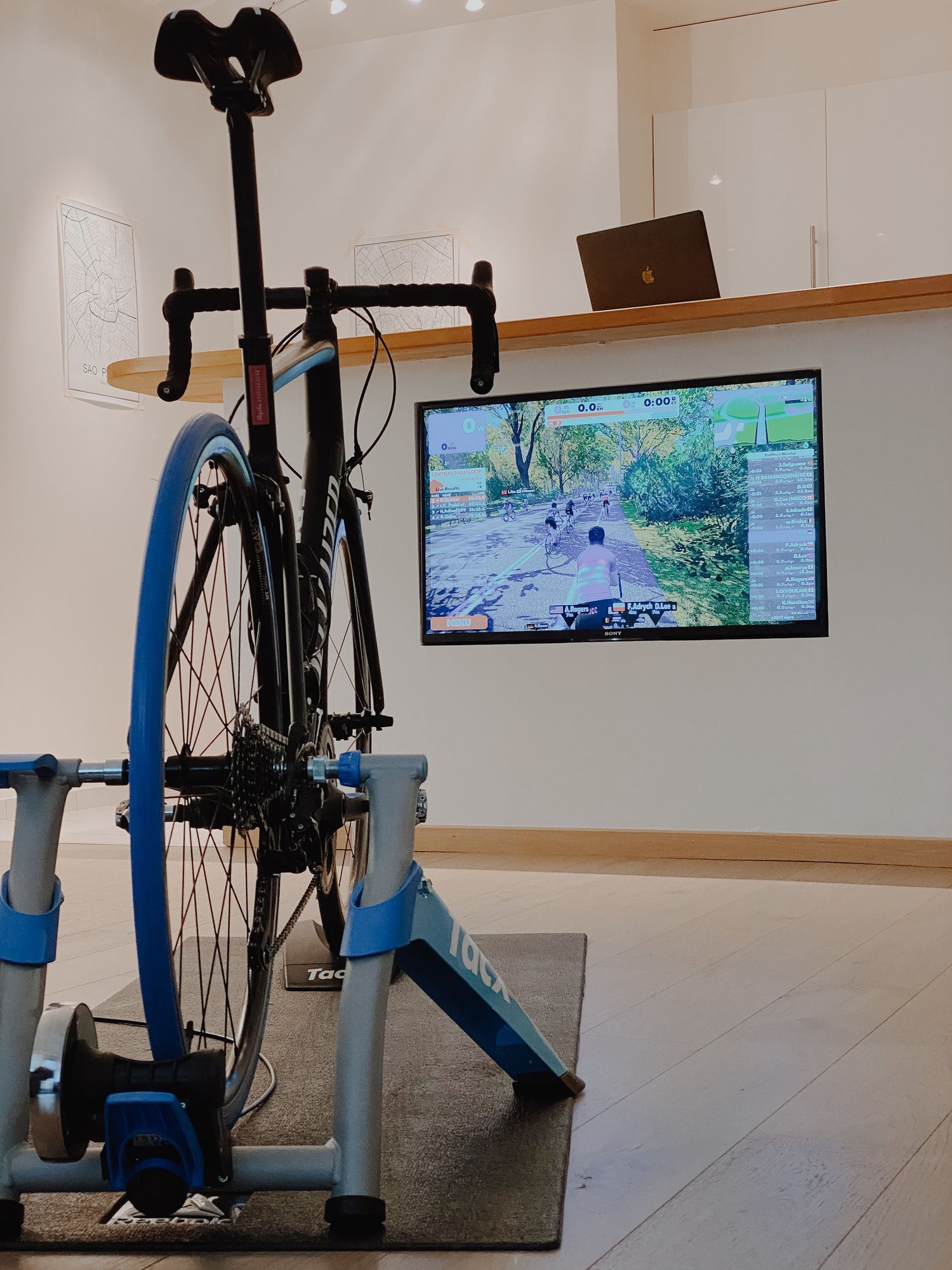 Road bike mounted on an indoor smart trainer in front of a virtual cycling screen