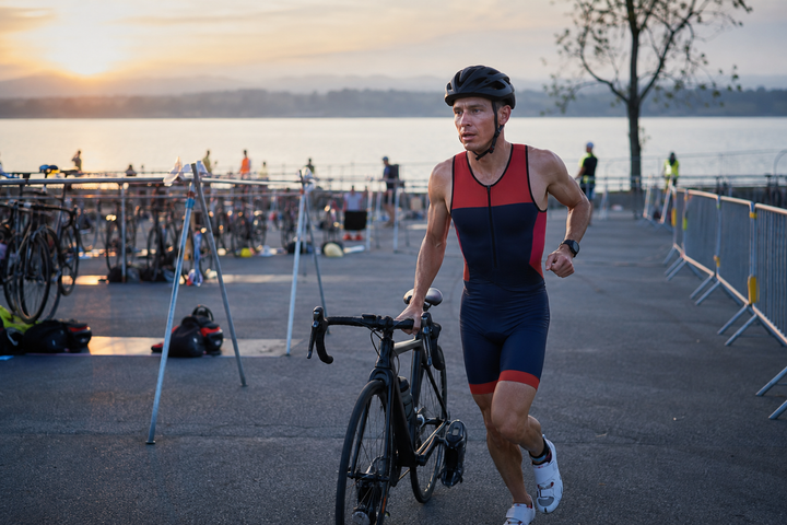 Triathlete running with a bike through transition on race morning