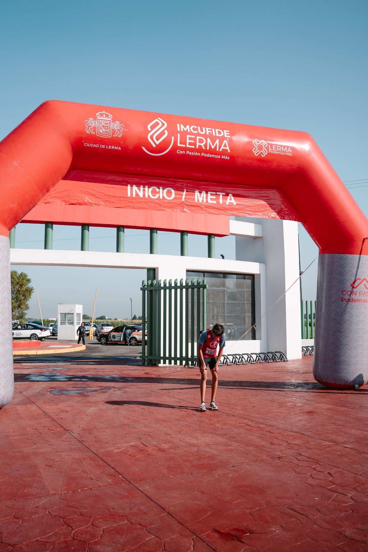 Exhausted endurance runner bending over at the finish line after a race