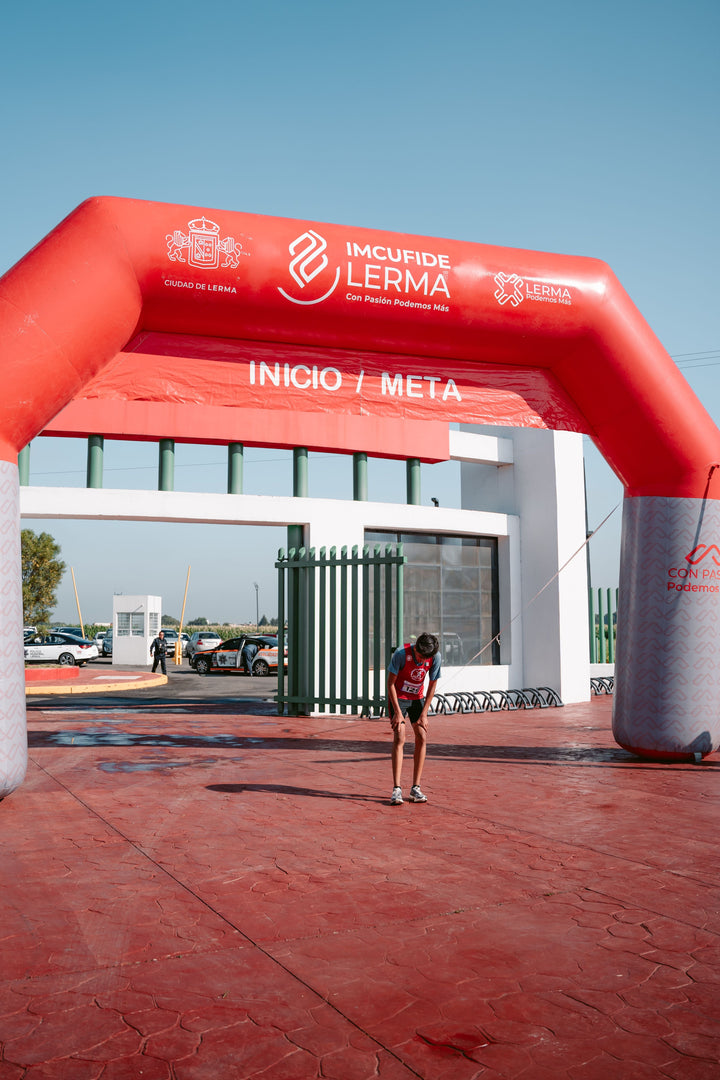 Exhausted endurance runner bending over at the finish line after a race